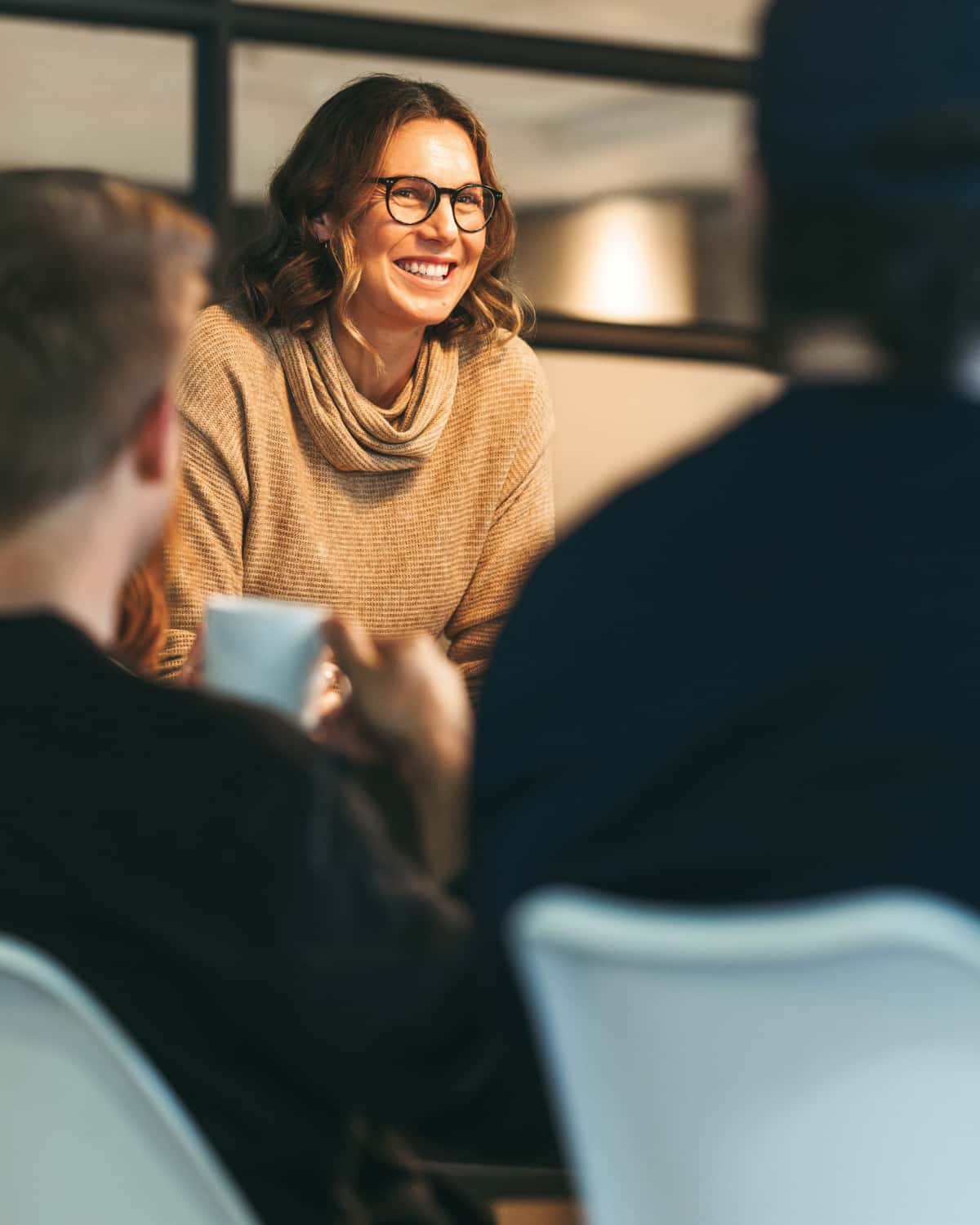 Woman smiling while conversing with others. 