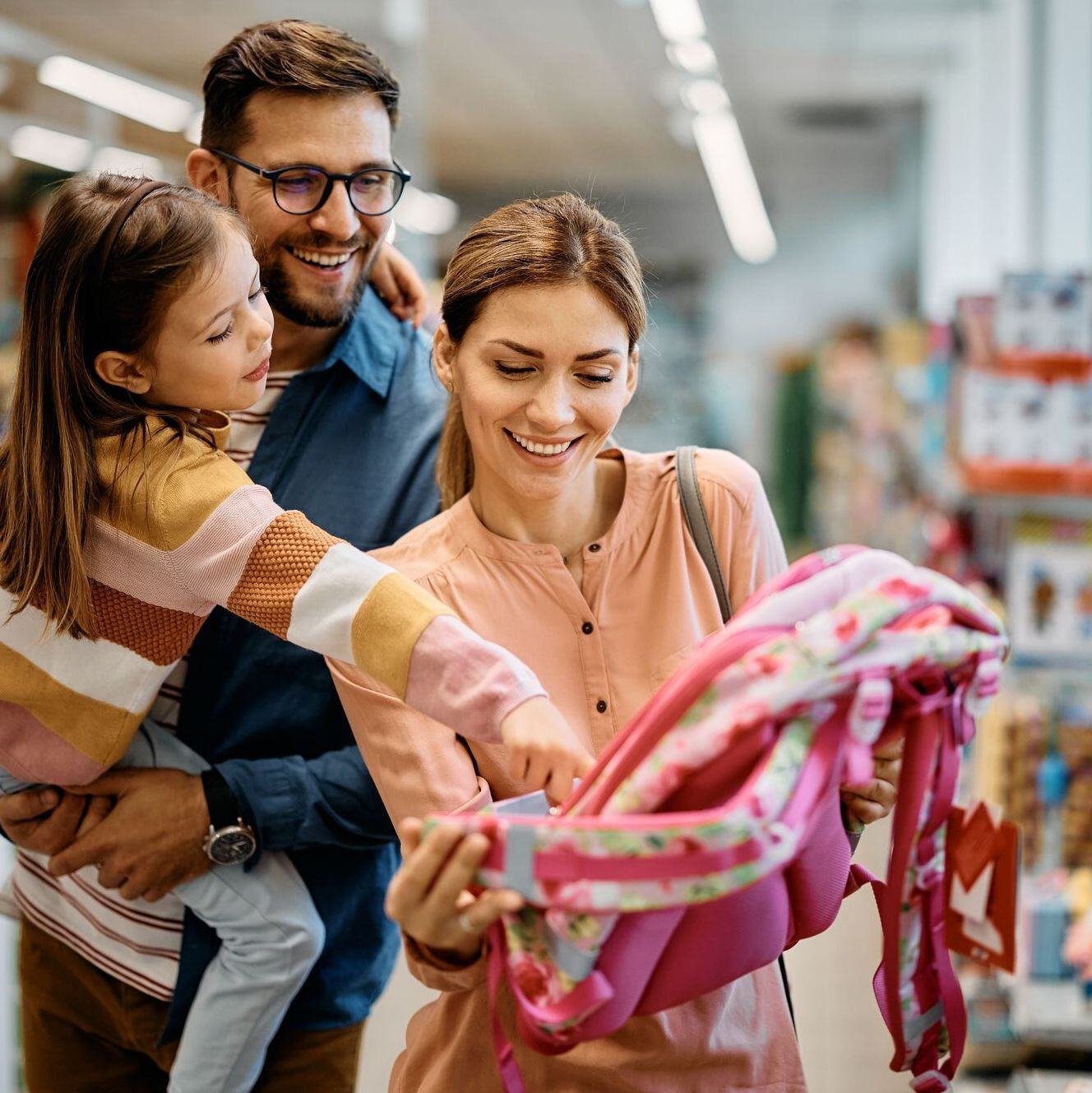 Parents holding Daughter, shopping for a new backpack