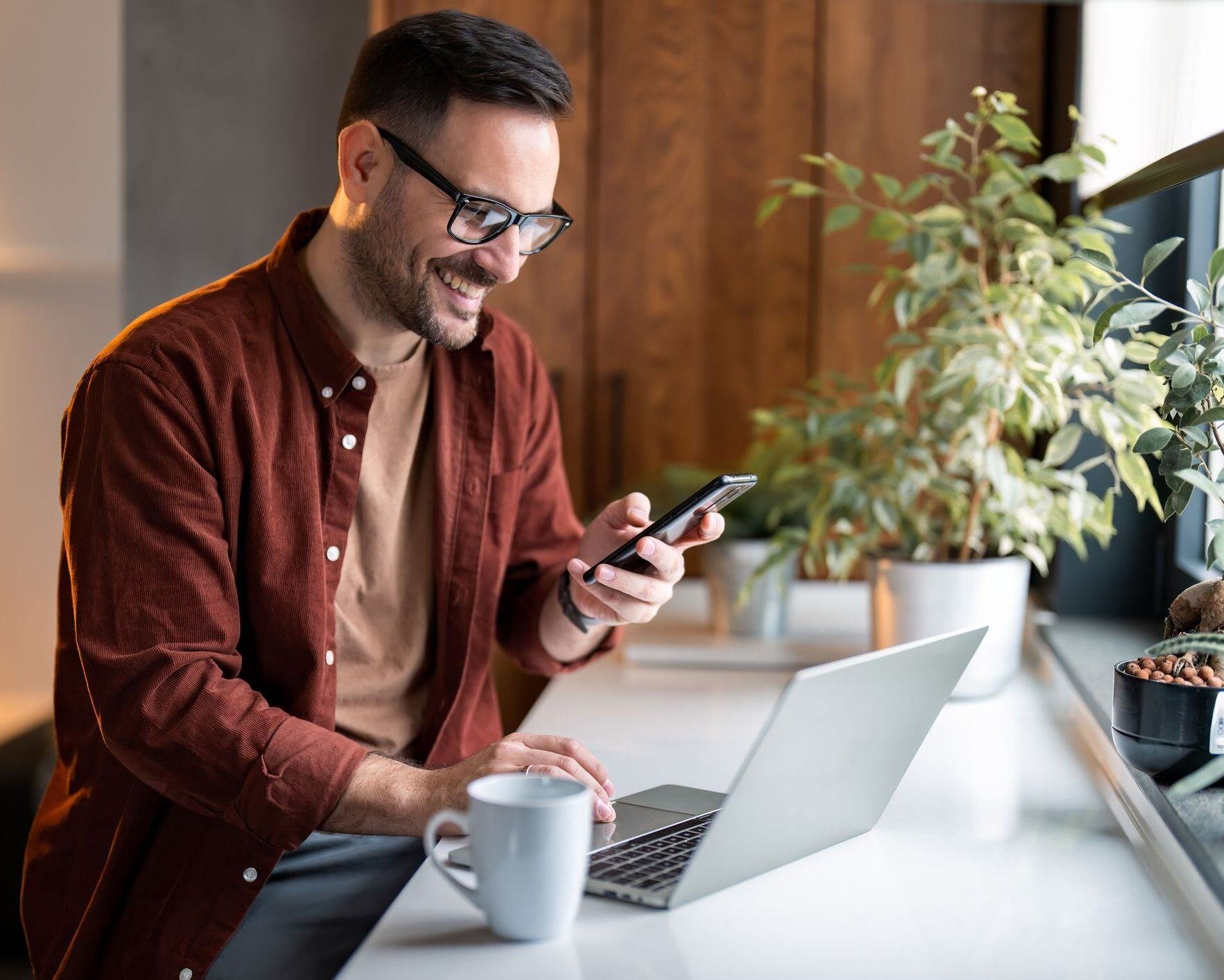 Man sitting at a desk on his phone and computer